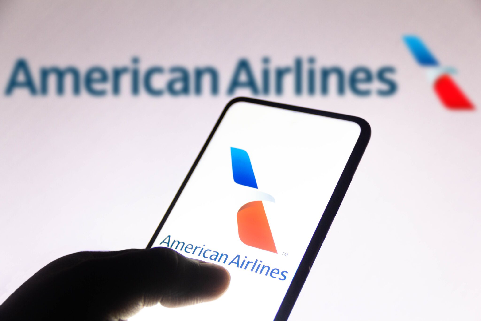 A person holding a smartphone with the American Airlines app. 