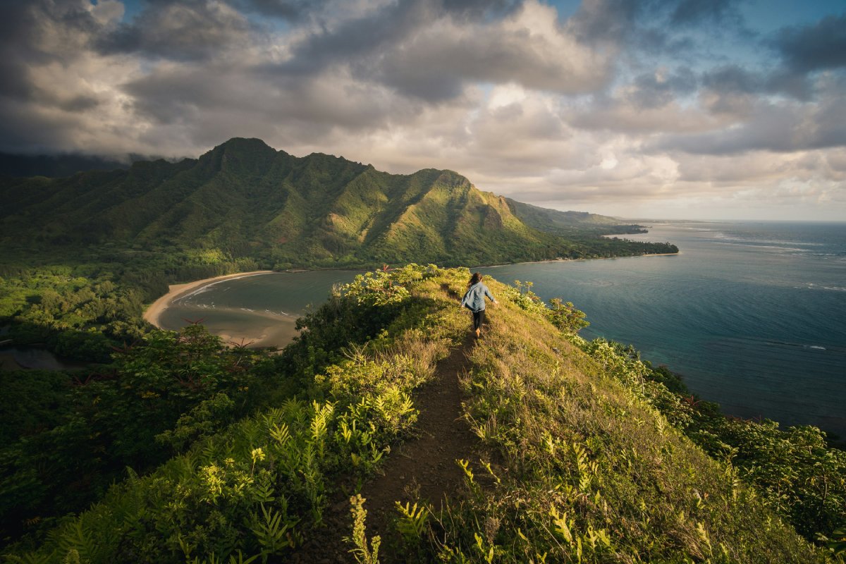 A woman hiking in Hawaii amid a sunset.